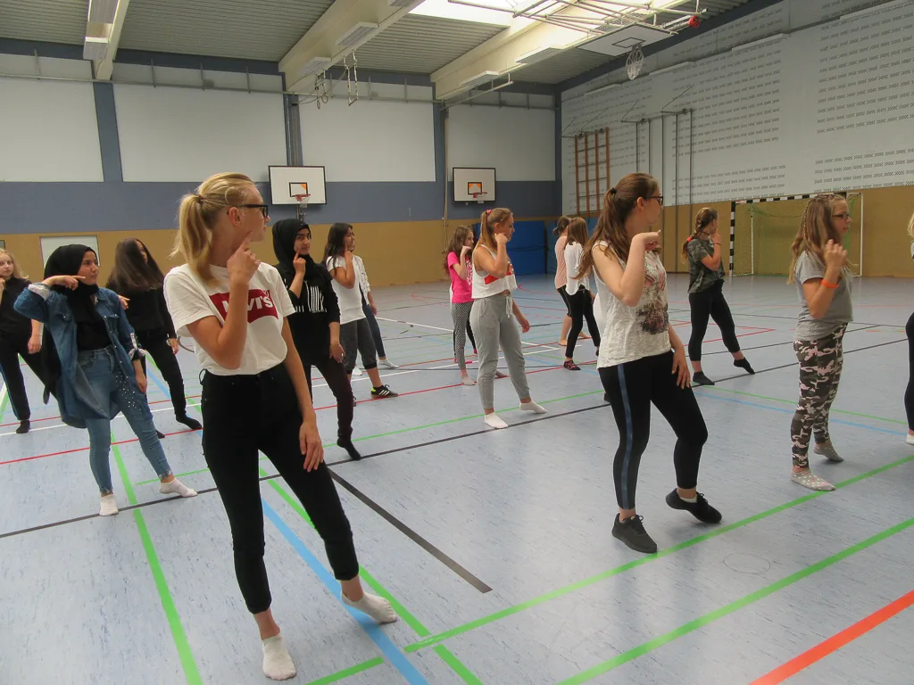 Jugendliche tanzen in der Sporthalle.